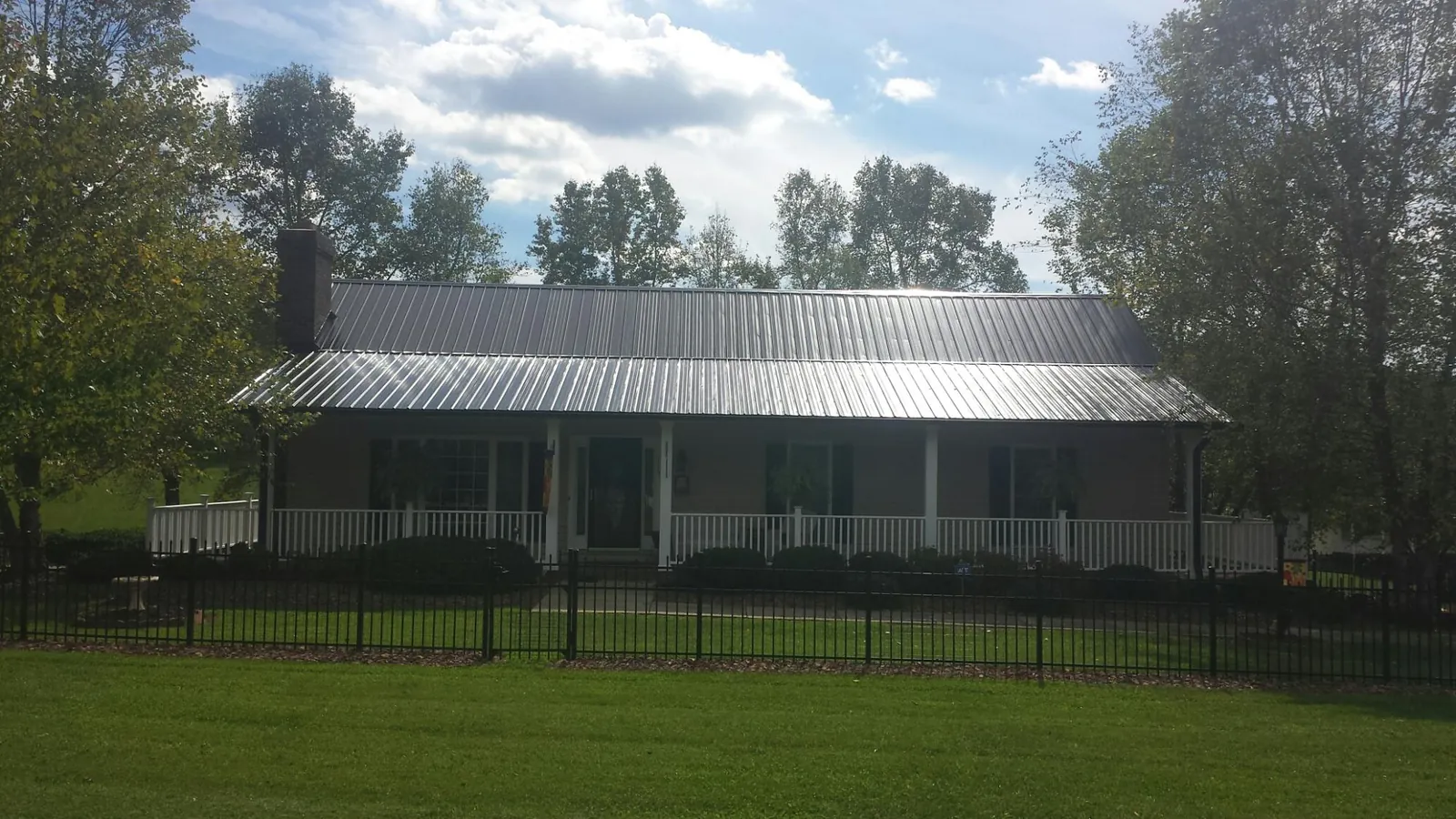 Gray metal roof on a brick ranch with a full width front porch in Alamo